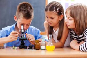 egy kisfiú és két kislány egy mikroszkóppal